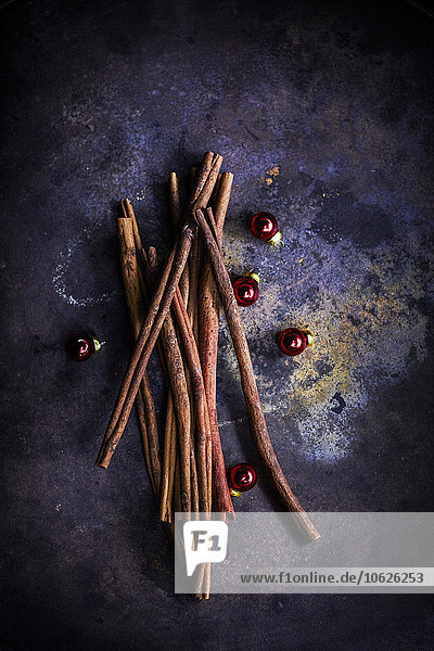 Cinnamon sticks and red Christmas baubles on dark background