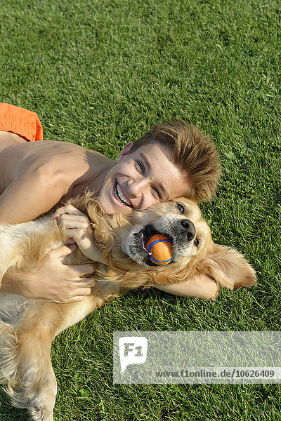 Teenage boy playing with Golden Retriever on lawn