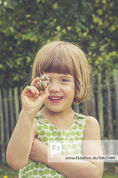 Portrait of smiling little girl holding vineyard snail
