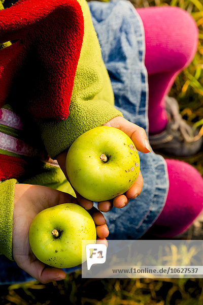 Little girl holding two green apples  close-up