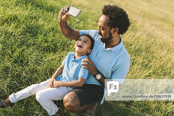 Vater und glücklicher Sohn auf einem Feld  der einen Selfie nimmt.
