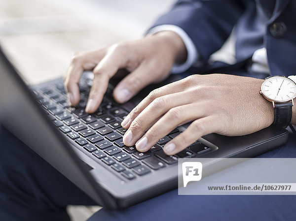 Germany  Cologne  Young businessman typing on laptop  close up