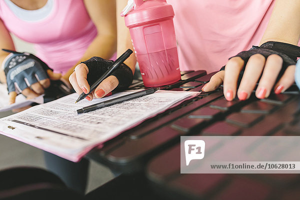 Close-up of two women planning their workout routine in gym