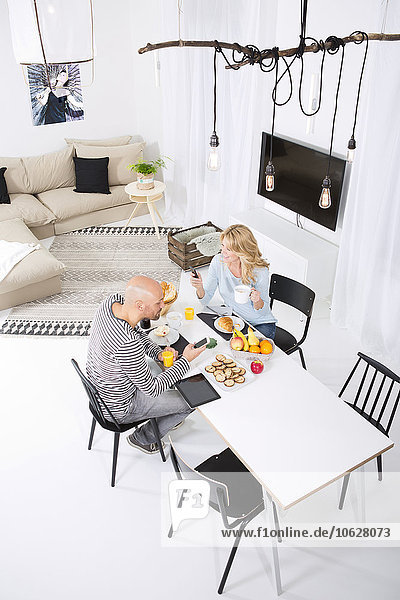 Paar am Frühstückstisch mit Smartphones