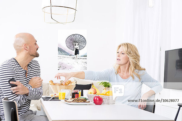 Paar am Frühstückstisch  Frau unzufrieden mit Ehemann mit Smartphone