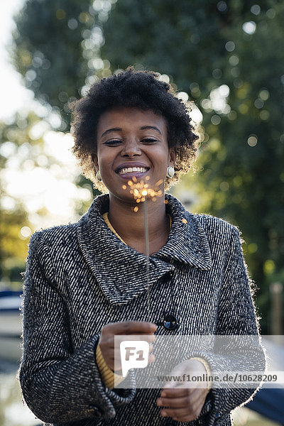 Schöne schwarze Frau beleuchtet Wunderkerzen im Freien