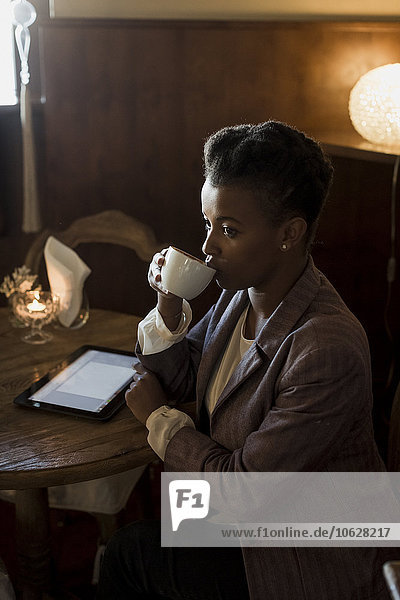 Junge Frau sitzt in einem Café und trinkt Kaffee.