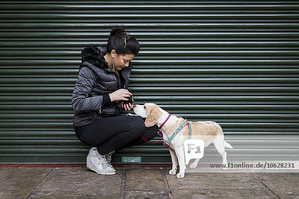 Frau und Hund auf dem Bürgersteig vor einem Rollladen