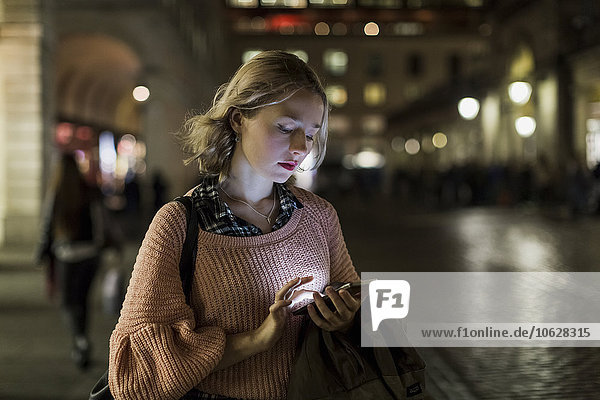 UK  London  young woman using smartphone on the street in the evening