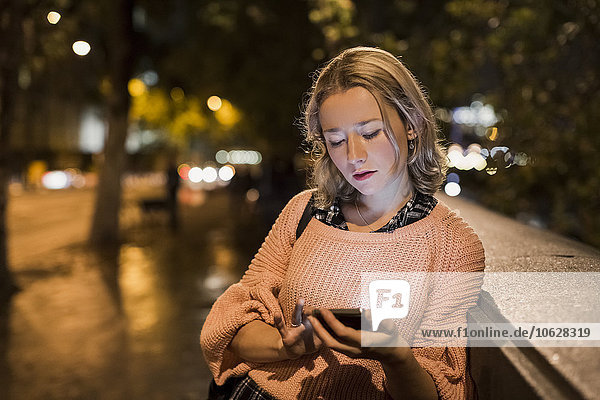 UK  London  young woman using her smartphone on the street at evening