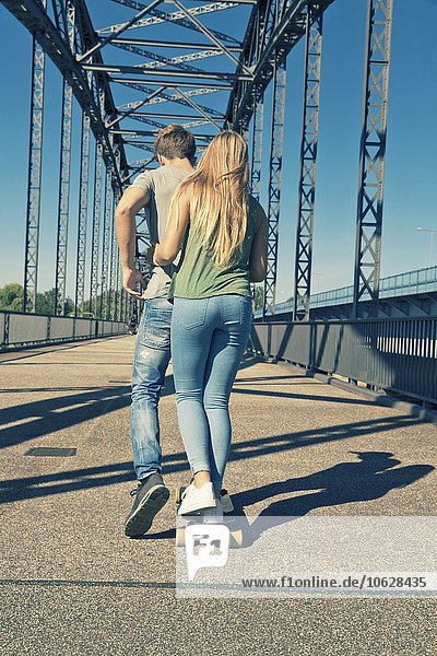 Rückansicht eines verliebten jungen Paares auf einem Skateboard