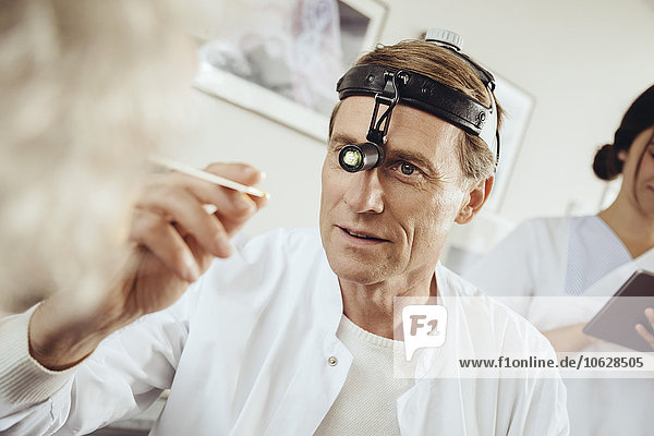 Doctor wearing surgical headlight examining patient