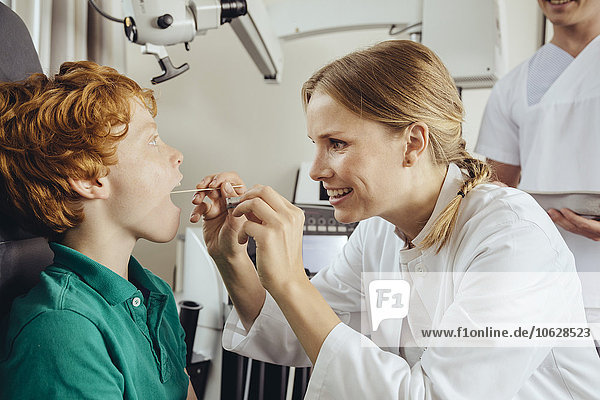 Female doctor examining little boy with with spatula