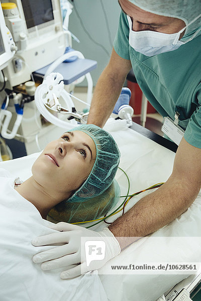 Operationsschwester beruhigender Patient auf dem Tisch im Operationssaal
