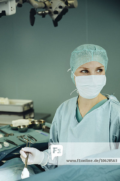 Chirurgin hält Klemme im Operationssaal während der Operation