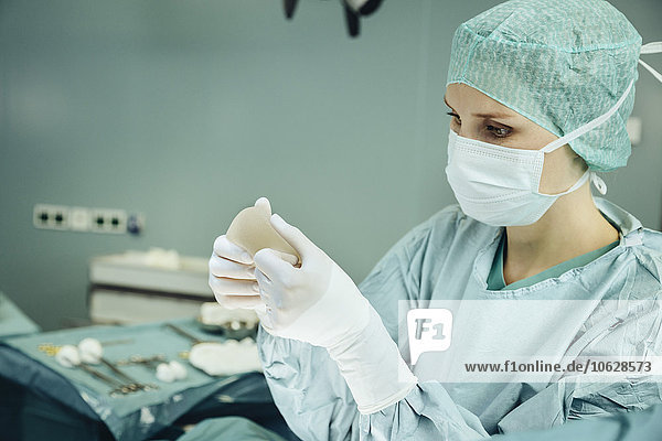 Chirurgin hält und kontrolliert Silikonimplantat während der Operation