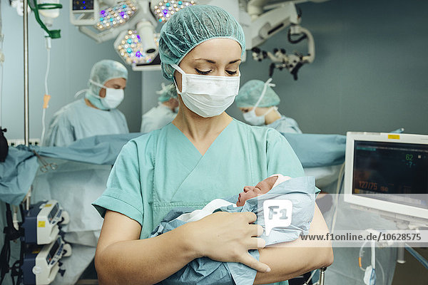 Operationsschwester mit Neugeborenen im Operationssaal