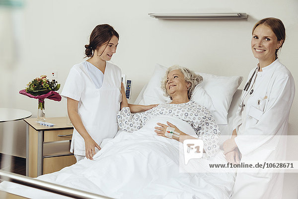 Senior woman in hospital talking to nurse and female dotor