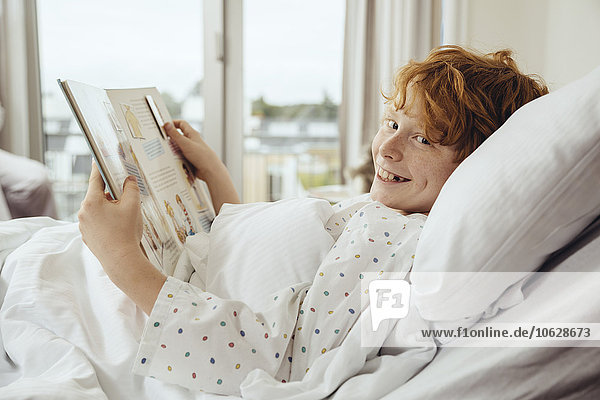 Kranker Junge liest Buch im Krankenhausbett liegend