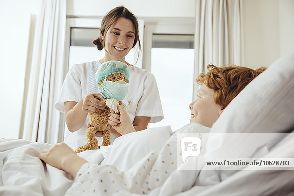 Boy in hospital bed receiving toy from nurse