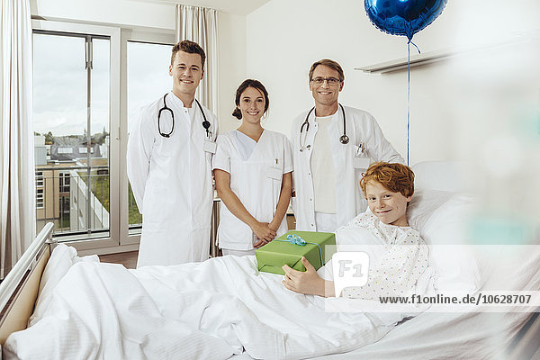 Ärzte im Krankenhaus stehen am Bett des kranken Jungen an seinem Geburtstag
