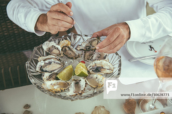 Hands of a man eating fresh oysters in a restaurant