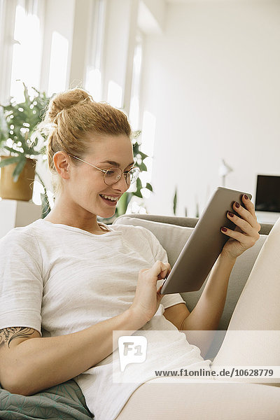 Junge Frau zu Hause  die auf ein digitales Tablett schaut  lacht