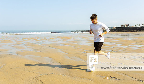 Spain  Asturias  Gijon  young man running on the beach