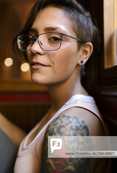 Portrait of tattooed young woman with nose piercing wearing glasses