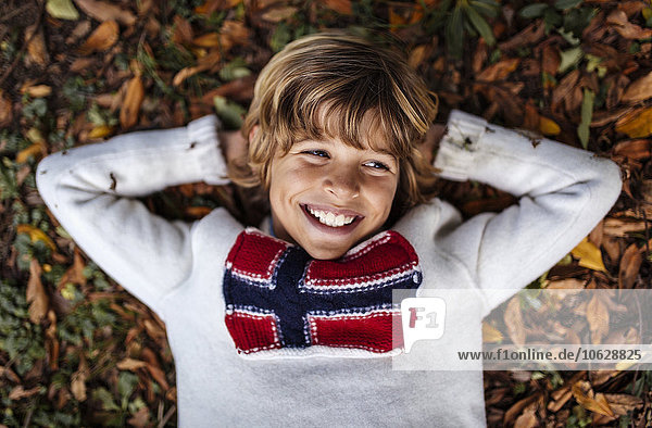 Porträt eines lächelnden blonden Jungen im Pullover mit norwegischer Flagge