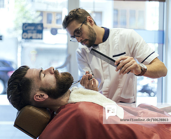 Barber cutting beard of a customer