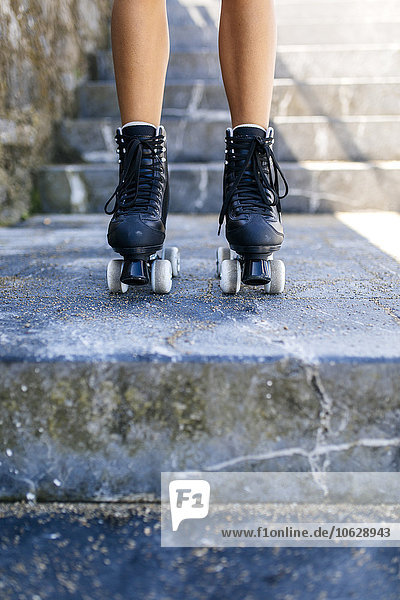 Beine eines Teenagermädchens mit Rollschuhen auf der Treppe