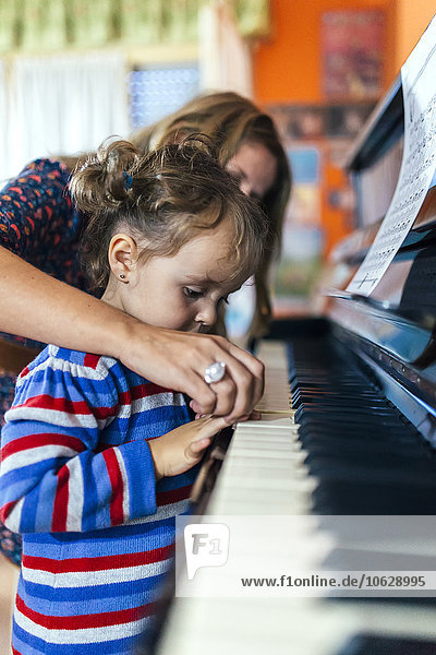 Woman and little girl playing piano together