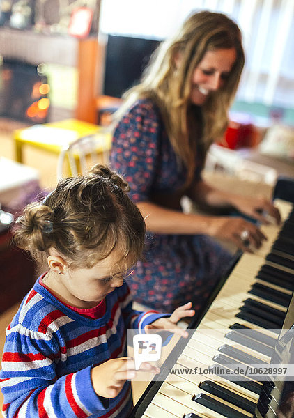 Woman and little girl playing piano together