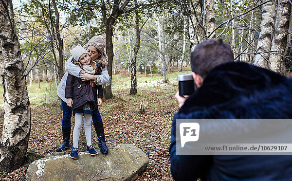Vater fotografiert Frau und Tochter im Wald