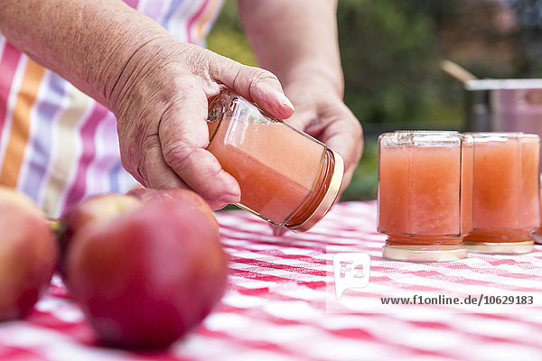 Seniorenfrau dreht Glas hausgemachte Apfelmus  Nahaufnahme