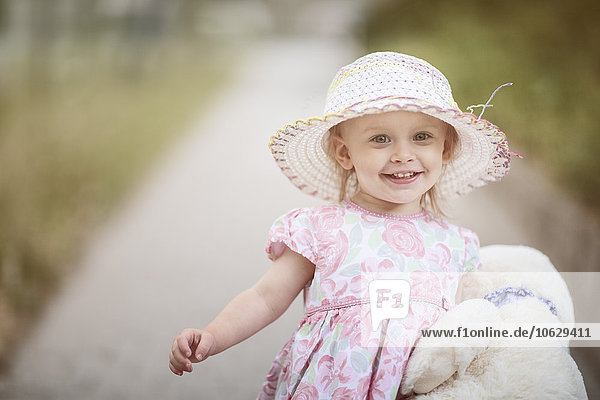 Porträt des lächelnden blonden Mädchens mit Hut und Sommerkleid mit Blumenmuster