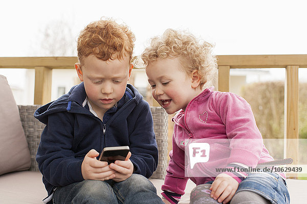 Kleiner Junge und Mädchen schauen auf das Handy