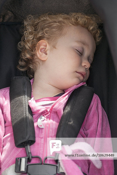 Kleines blondes Mädchen schlafend im Autositz
