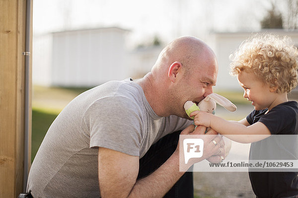Vater und kleine Tochter spielen mit Plüschtieren