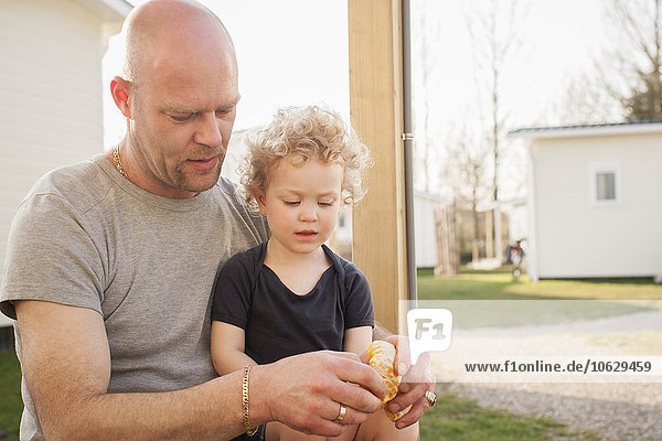 Vater und kleine Tochter mit Croissant