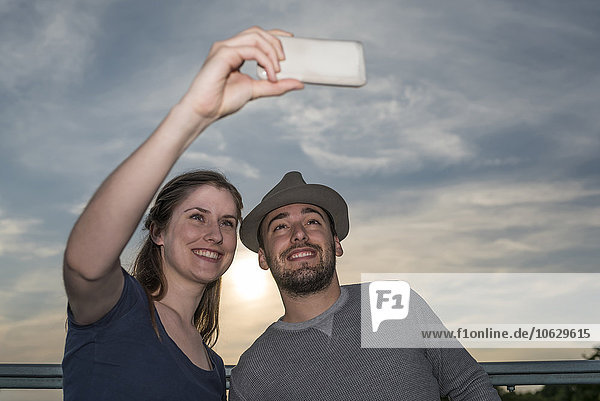 Lächelndes junges Paar,  das einen Selfie mit Smartphone nimmt