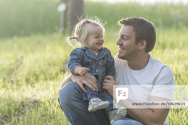 Father and his little daughter having fun on a meadow