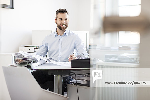 Smiling man at desk with construction plans