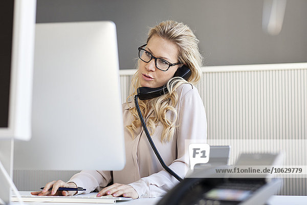 Blond woman in office on the phone