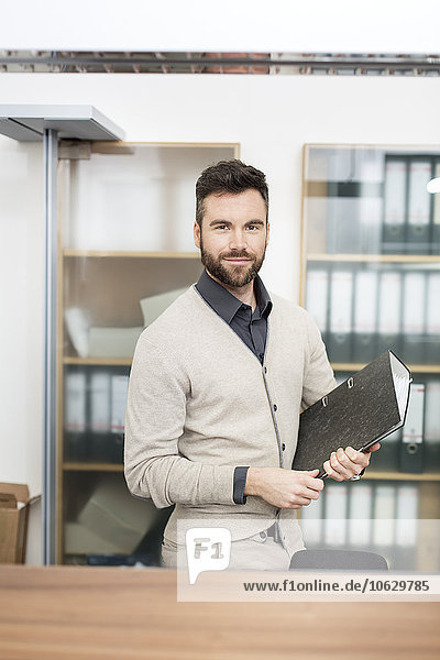 Man in office holding file folder