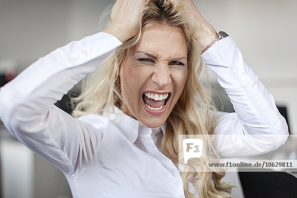 Blond woman in office tearing her hair out