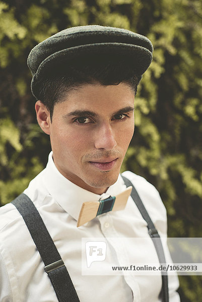 Portrait of elegant young man wearing beret and a wooden bow tie