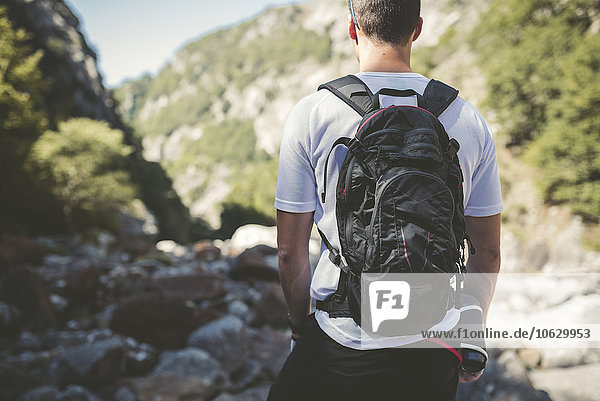 Ultra runner in mountains carrying backpack  looking at view