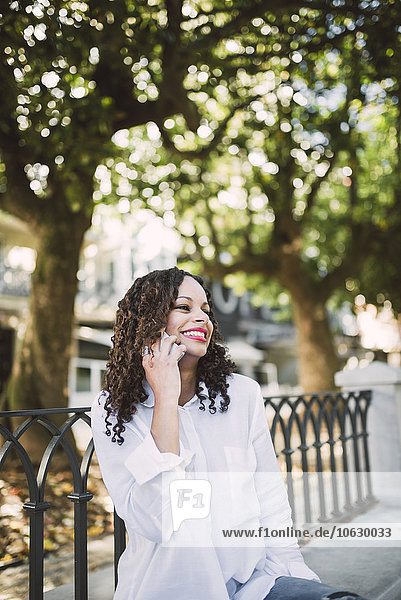 Portrait of smiling woman telephoning on a park bench